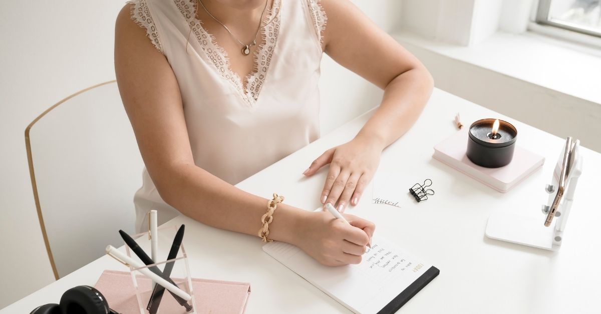 woman making notes on a notepad on a white desk